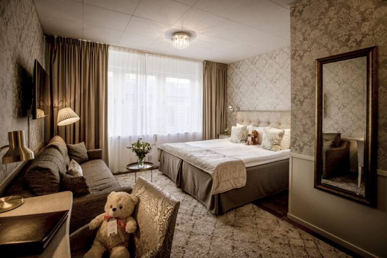 Hotellrum med dubbelsäng och extrabädd i ljusa färger och skira gardiner
