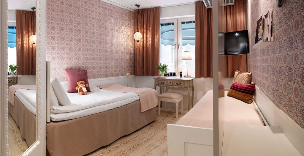 Hotellrum med enkelsäng och dagbädd samt skrivbord